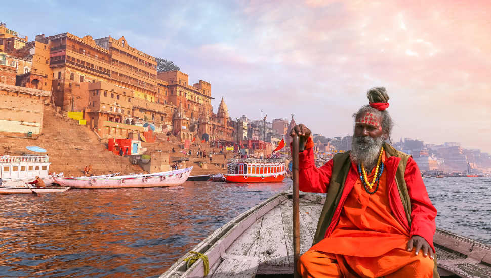 Indian Sadhu baba on boat on river Ganges overlooking the historic Varanasi city