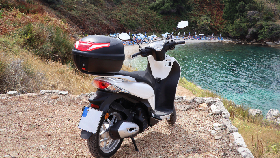 Scooter on clifftop, overlooking beach in Corfu